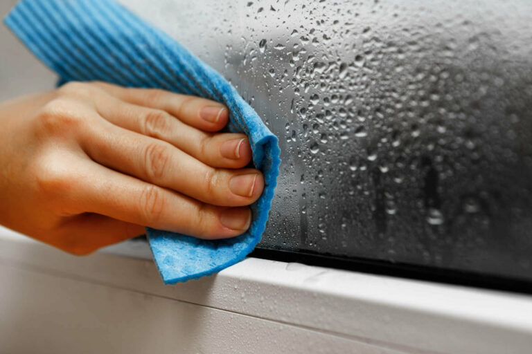 Wiping off window condensation with a rag.