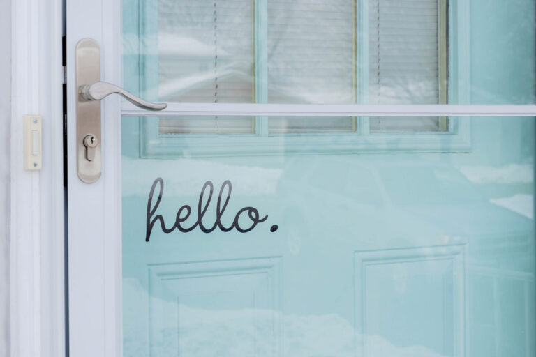 Close up of a storm door with Hello written on the main door.